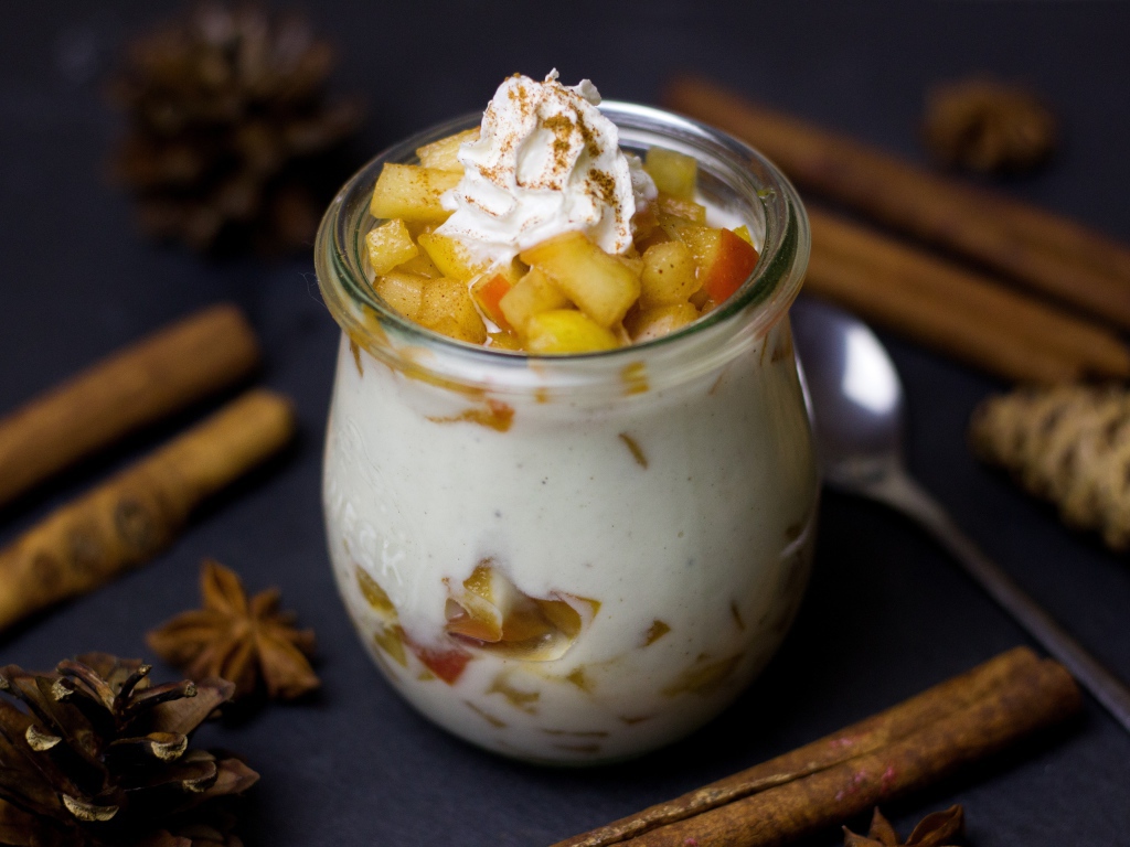 Десерт из йогурта с фруктами на столе с пряностями