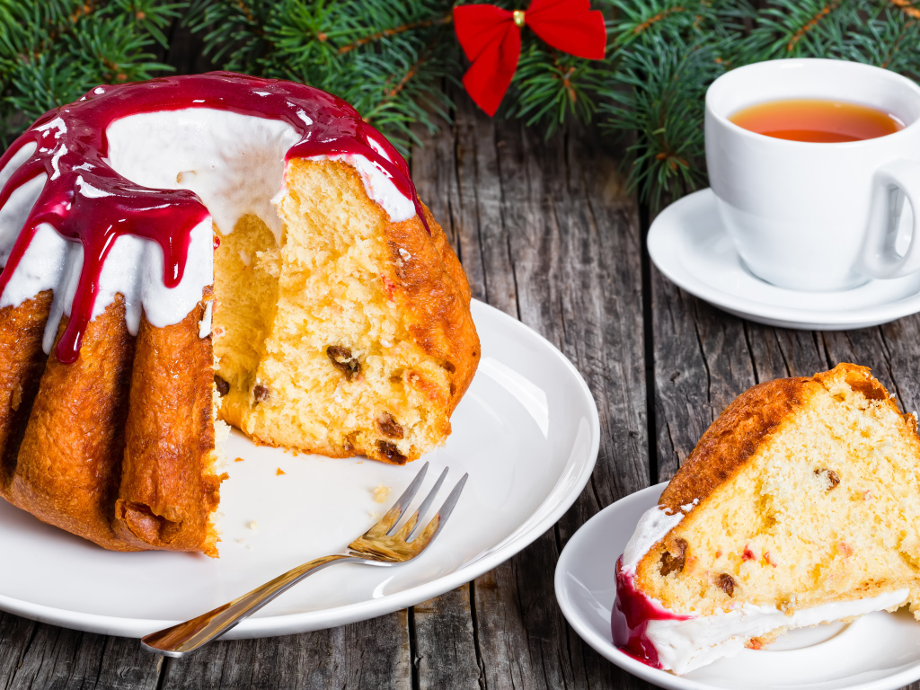 Праздничный кекс с глазурью на столе с чашкой чая