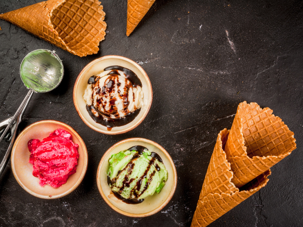 Шарики мороженого с вафельными рожками на столе 