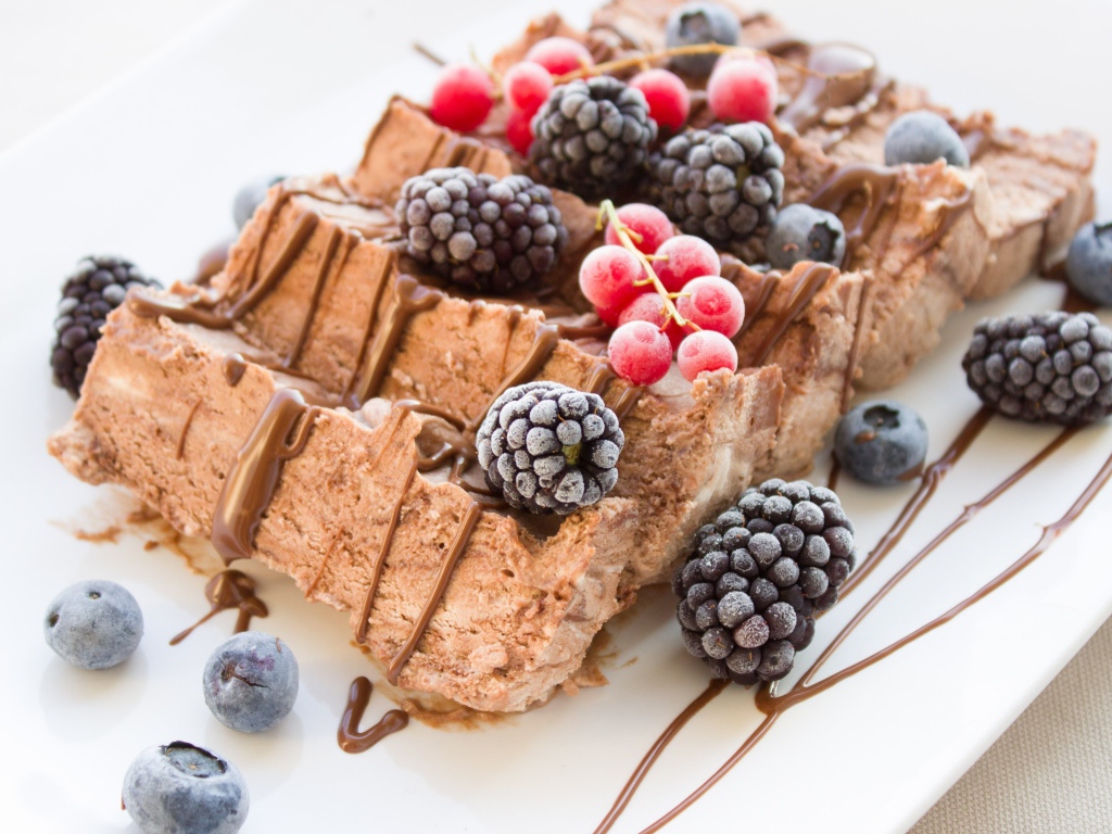 Мороженое с ягодами ежевики и красной смородины на белой тарелке 