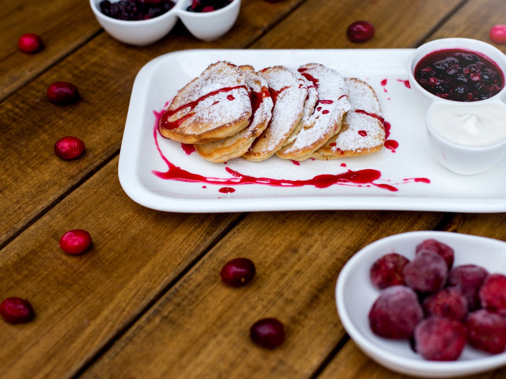 Оладьи с сахарной пудрой и вареньем на белой тарелке