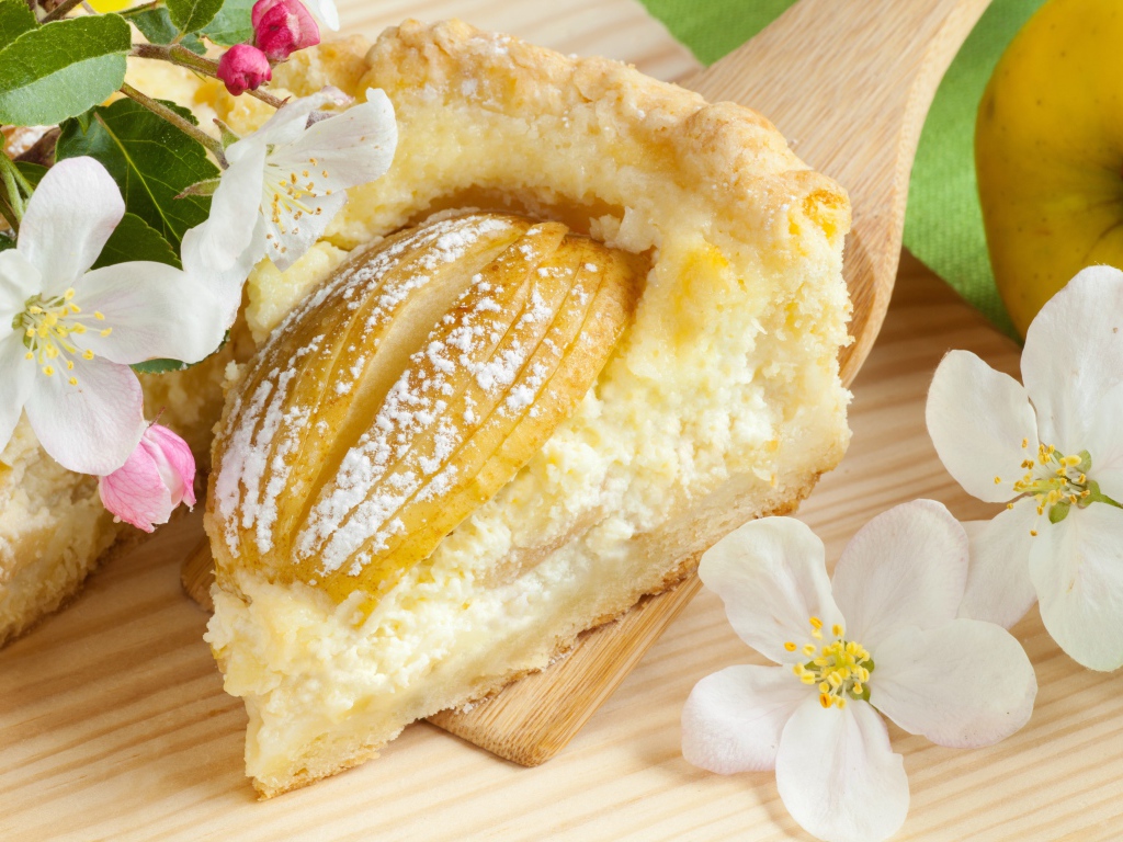 Кусок пирога с яблоками на деревянной лопатке с цветами яблони