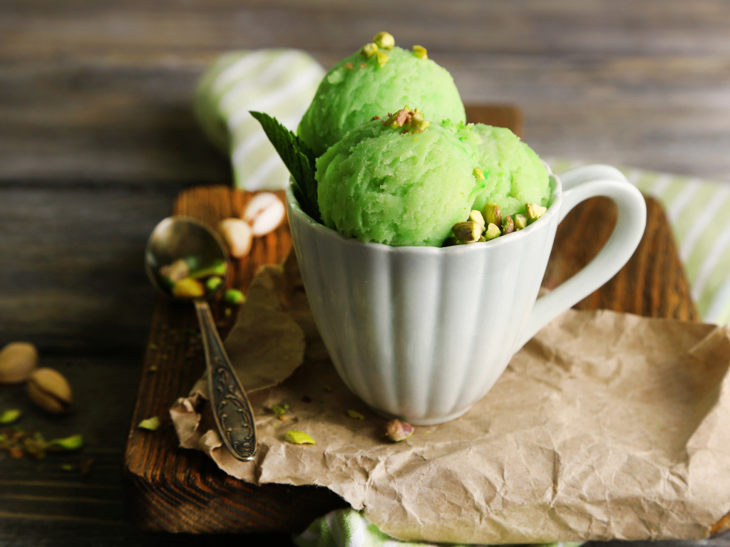 Фисташковое мороженое в белой чашке на столе