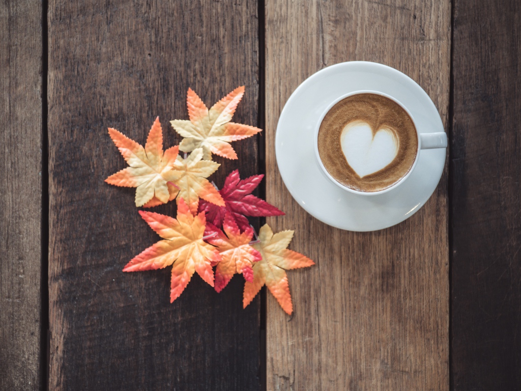 Чашка кофе на деревянном столе с желтыми листьями