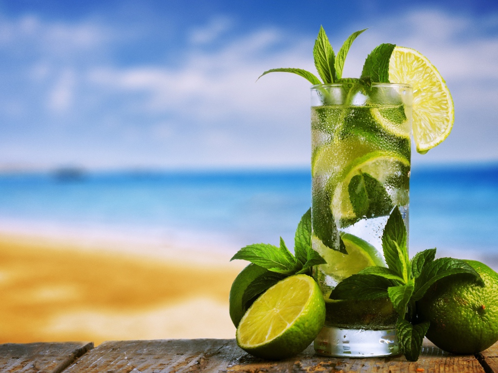 Стакан холодного мохито на столе с мятой и лаймом