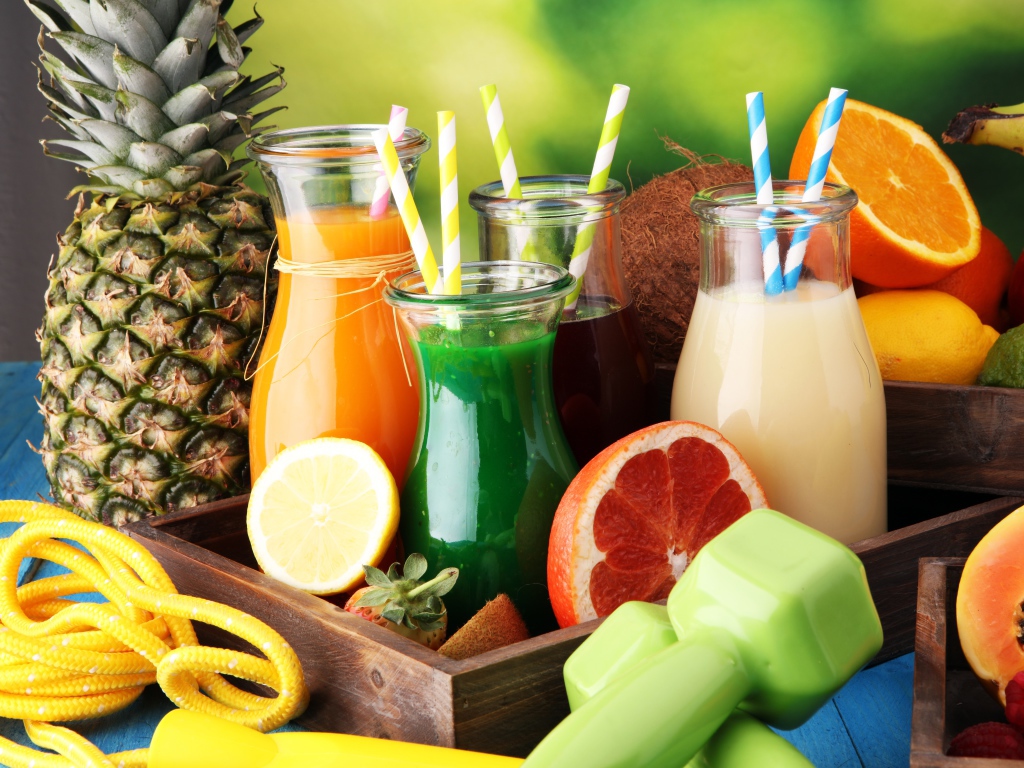 Коктейли в бутылках с трубочками на столе фруктами