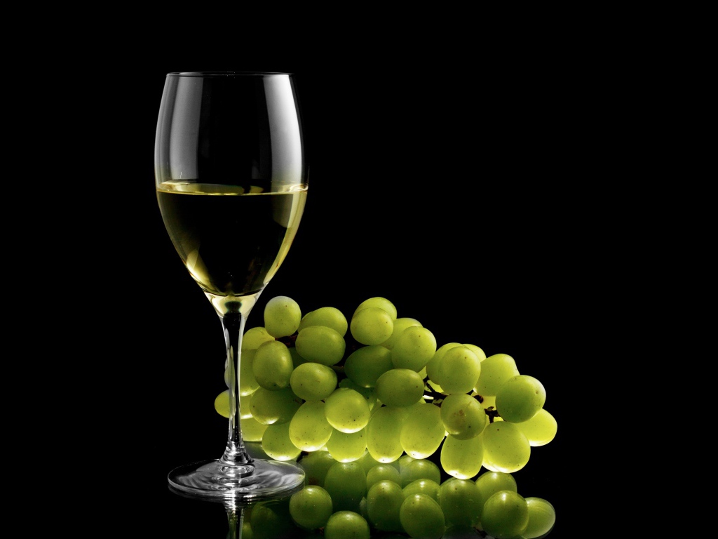 Бокал белого вина с белым виноградом на черном фоне