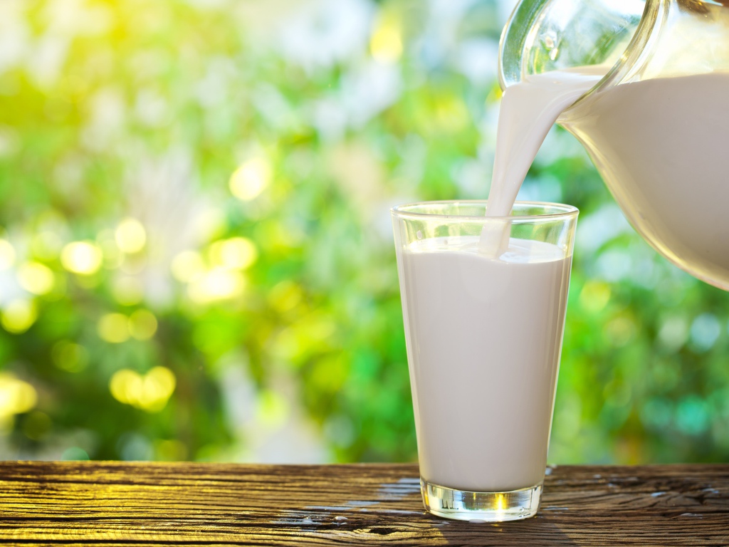 Молоко наливают в стеклянный стакан на столе