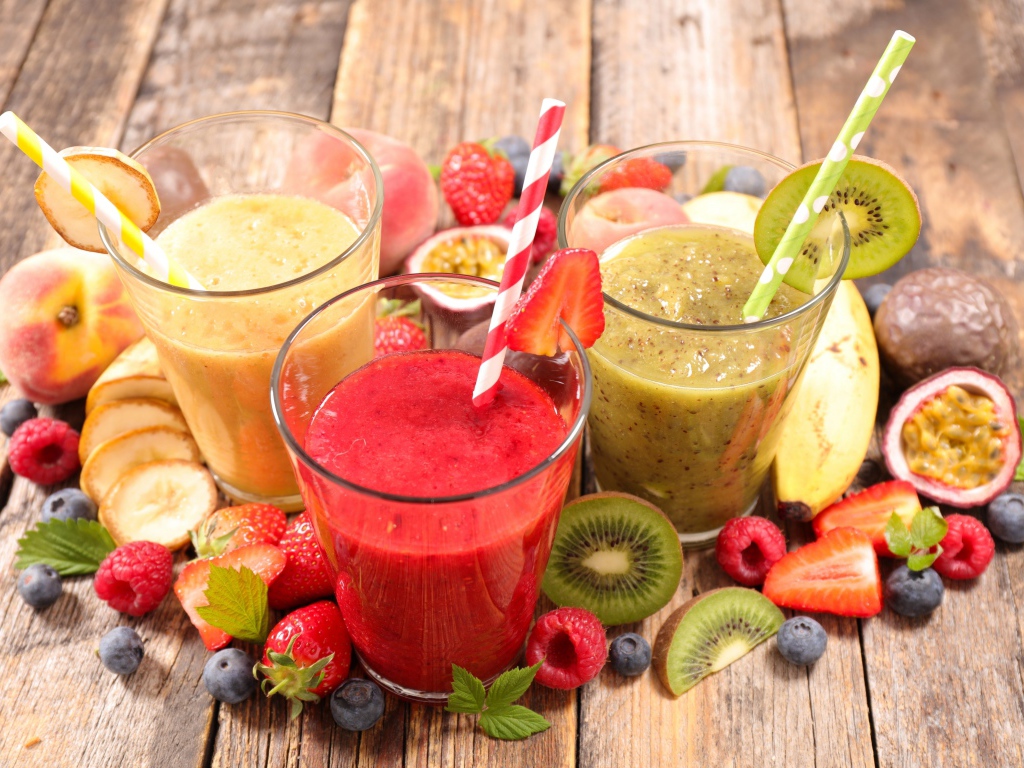 Смузи в стаканах с трубочками на столе со свежими фруктами