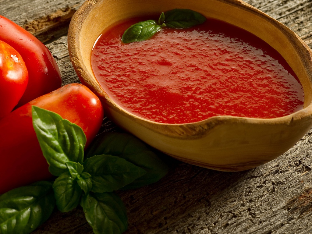 Томатный сок в деревянной посуде на столе с помидорами и базиликом