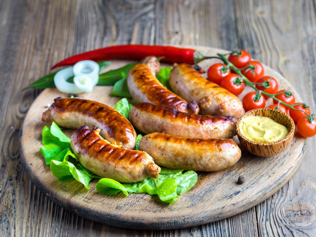 Сосиски барбекю с красным перцем и помидорами на разделочной доске