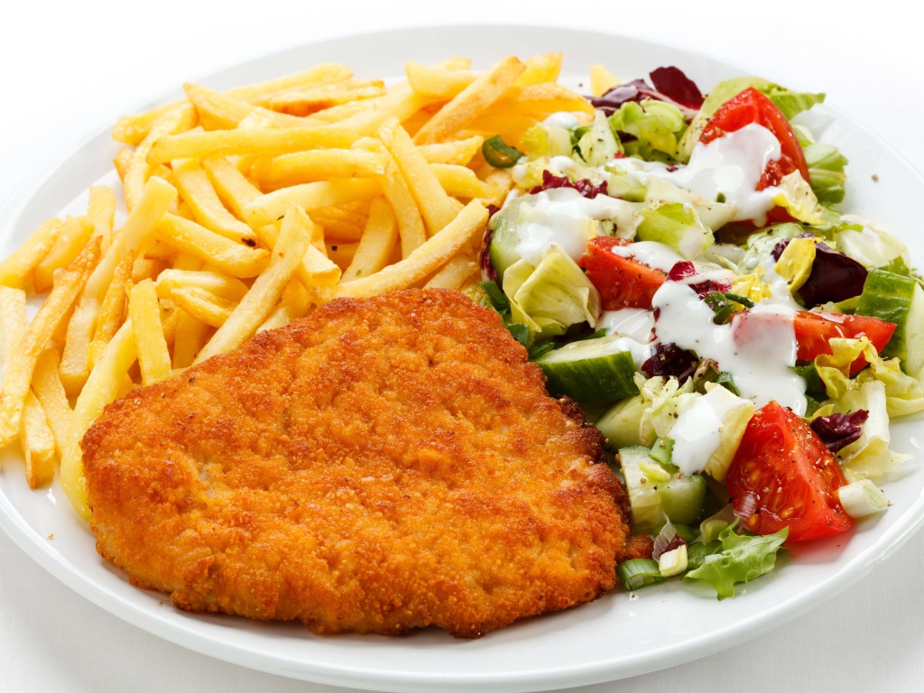 Отбивная на тарелке с картофелем фри и салатом