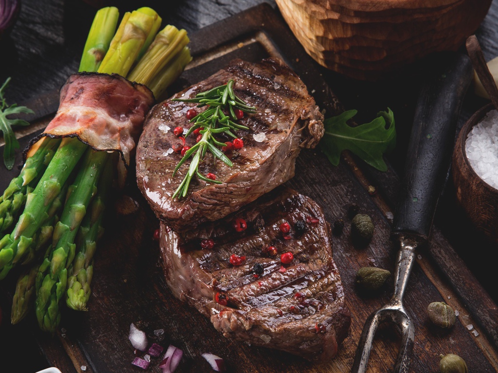 Жареное мясо с зеленой спаржей на столе 