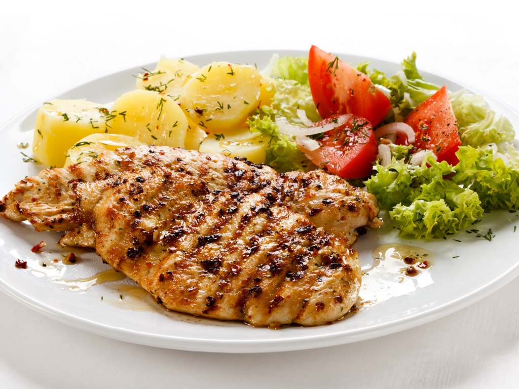 Жареная куриная грудка с овощами на белом фоне