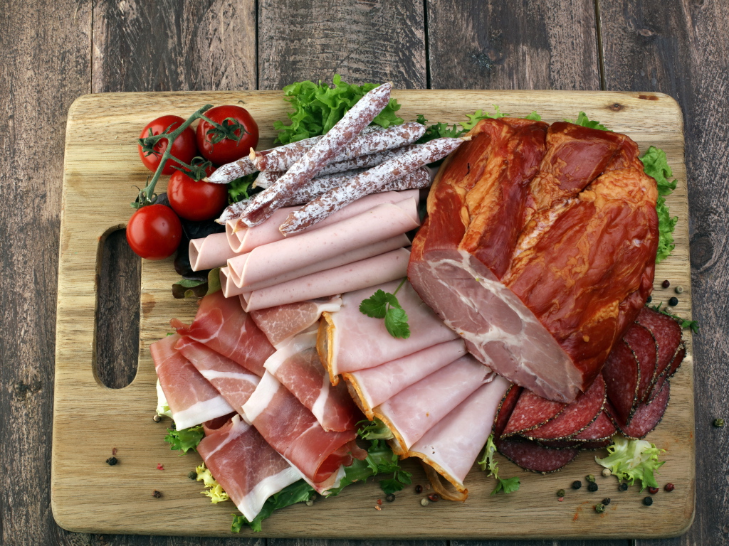 Мясная нарезка на разделочной доске с помидорами