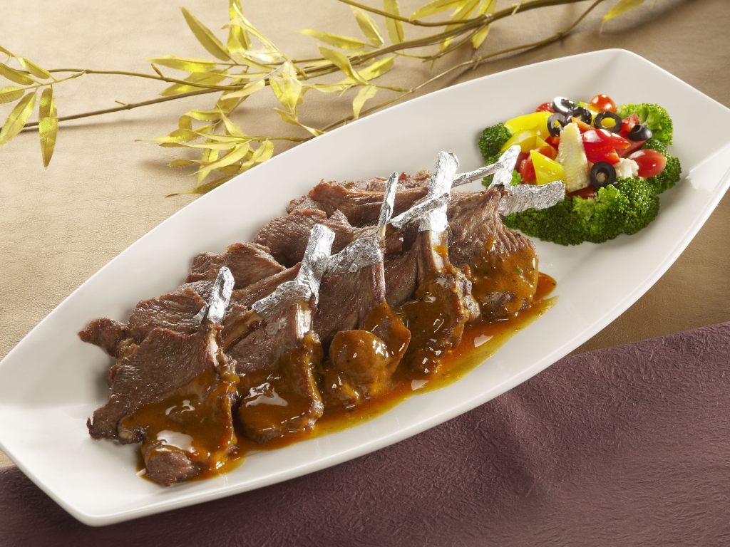 Мясо на белой тарелке с соусом и овощами 