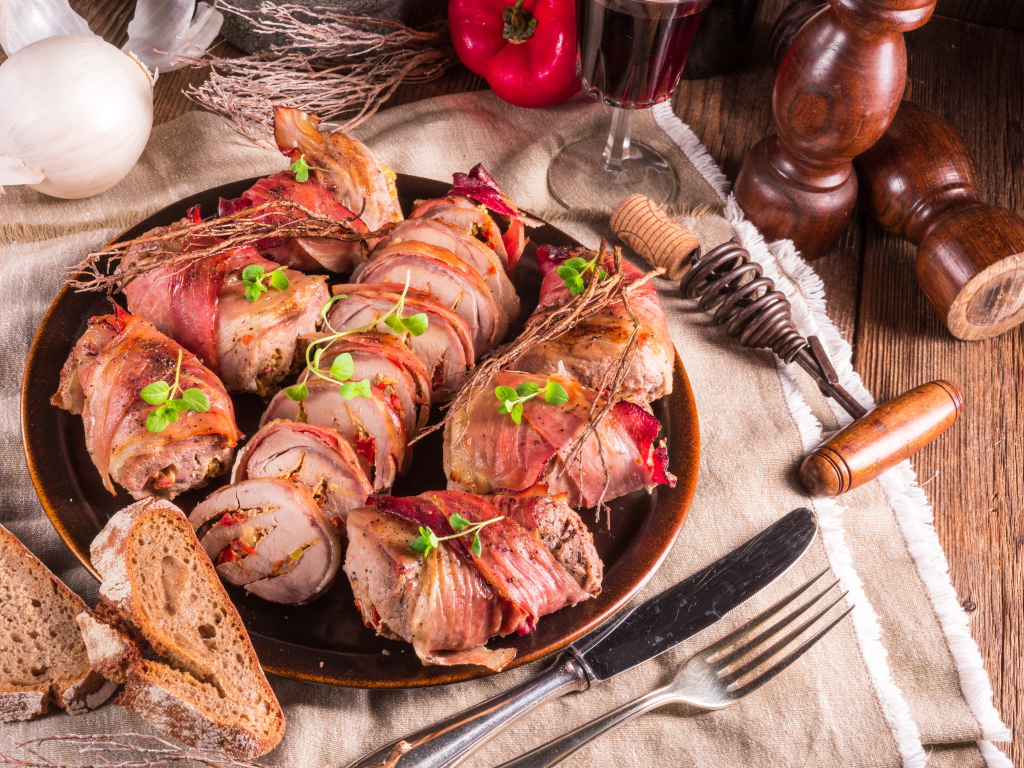 Нарезанные мясные рулеты на столе с хлебом