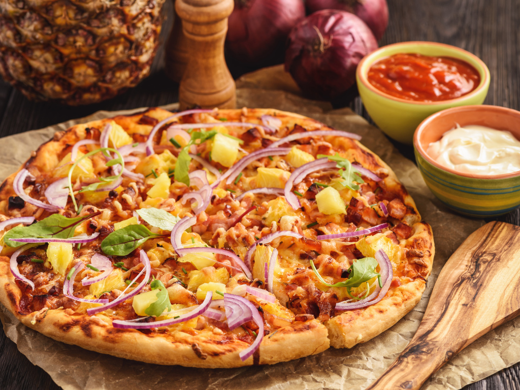 Пицца с ананасами и луком на столе с соусом