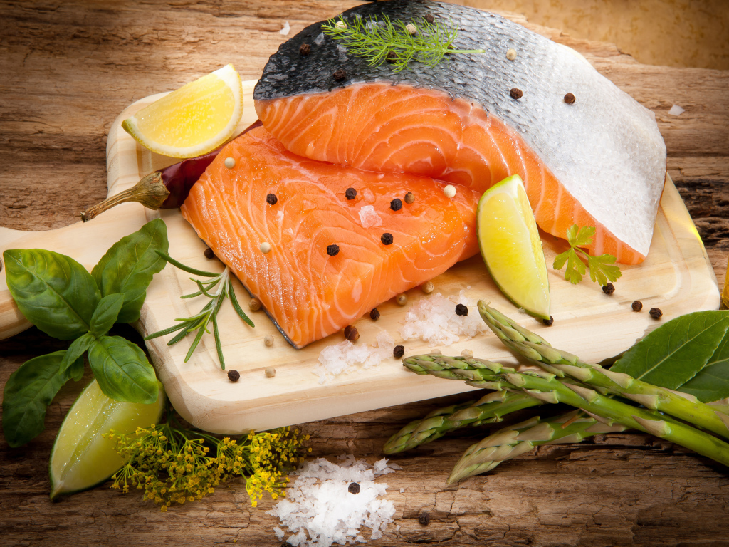 Филе красной рыбой на столе со спаржей и лаймом