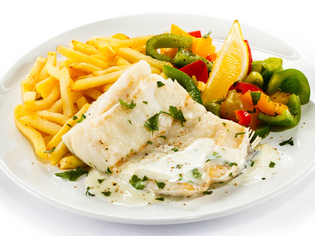 Филе рыбы на тарелке с картофелем и салатом на белом фоне