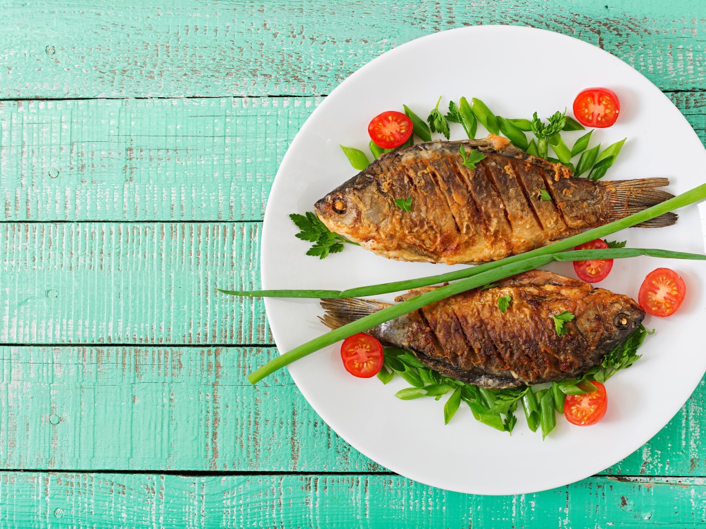 Fried fish with tomatoes and herbs on the table