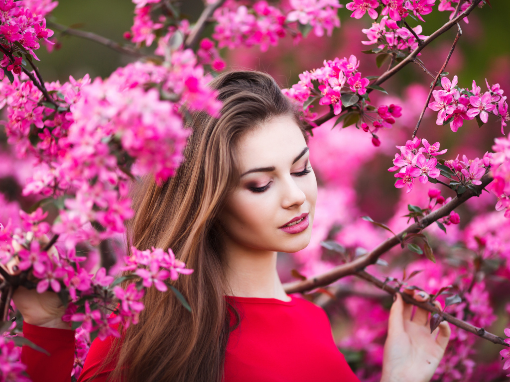 Красивая нежная шатенка у цветущей розовыми цветами ветки