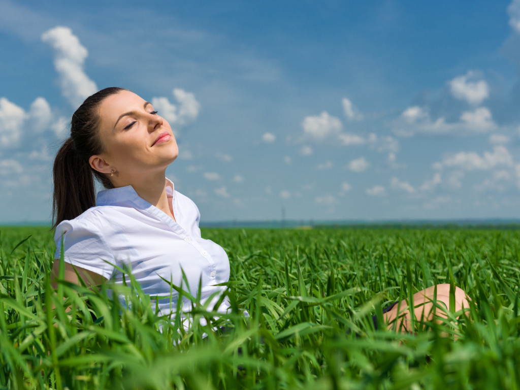 Красивая девушка нежится на солнце в зеленой траве