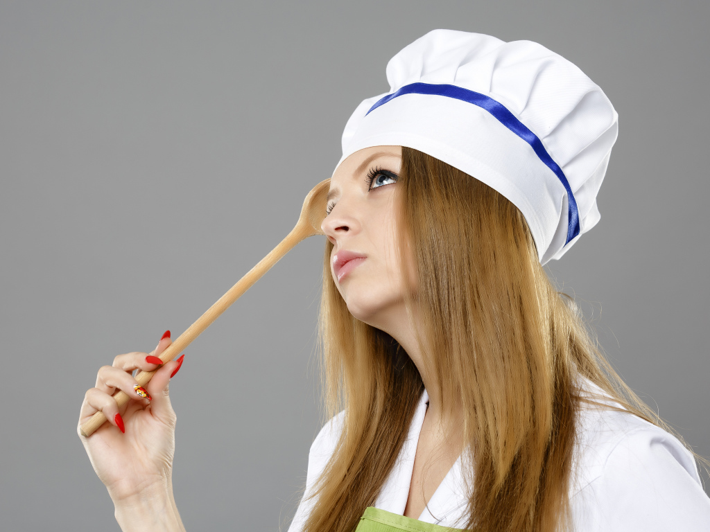 Красивая девушка в костюме повара на сером фоне