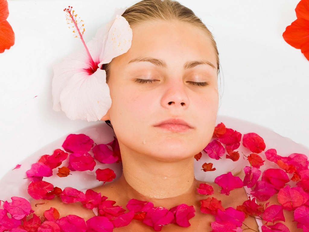 Красивая девушка в ванной с лепестками розы 