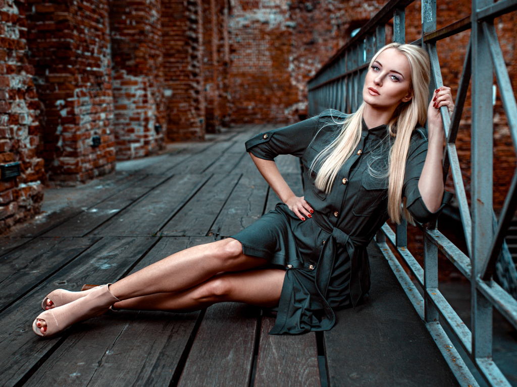 Красивая девушка сидит на деревянном полу