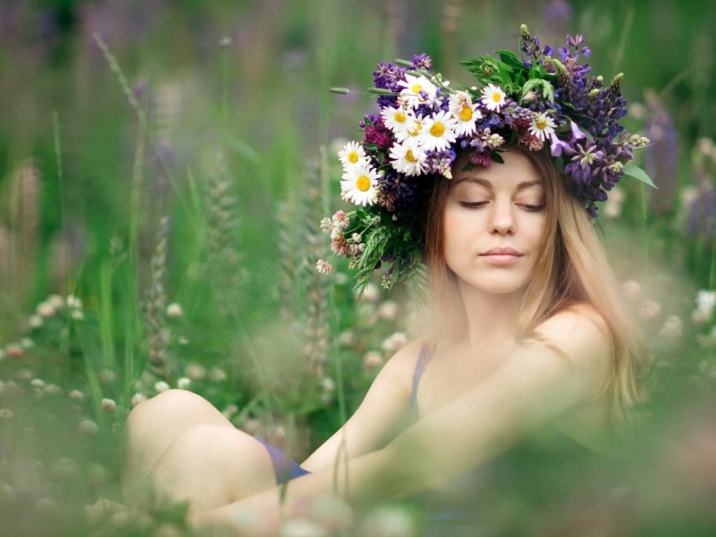 Красивая девушка с венком из полевых цветов на голове летом 