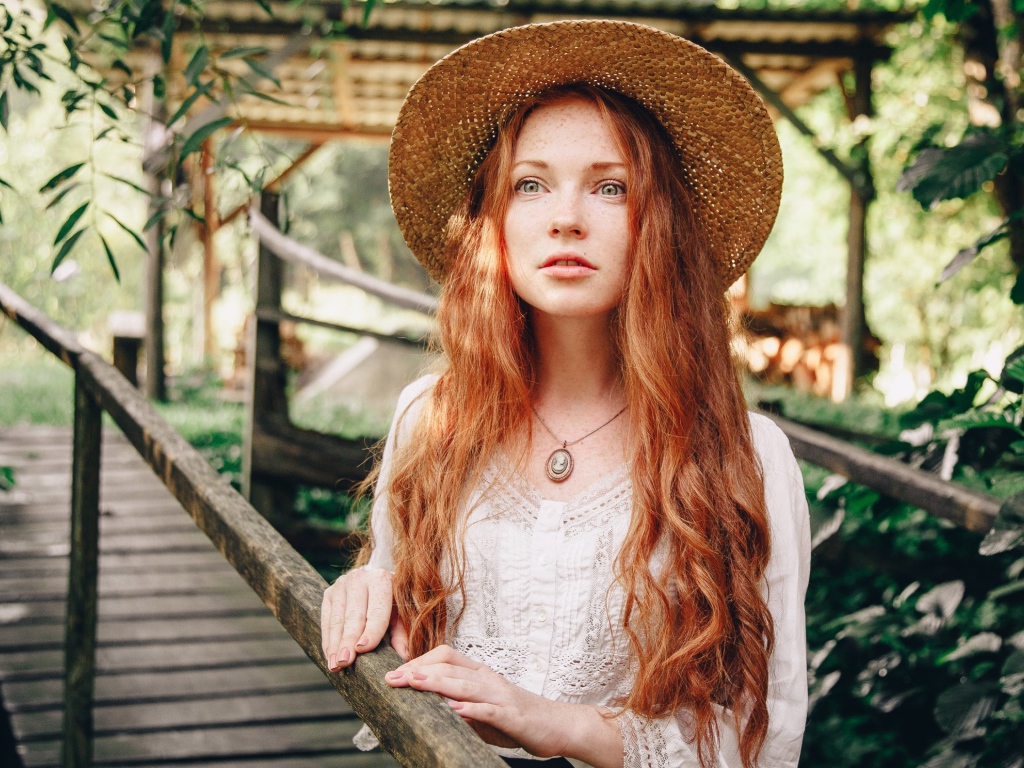 Красивая рыжеволосая девушка в соломенной шляпе