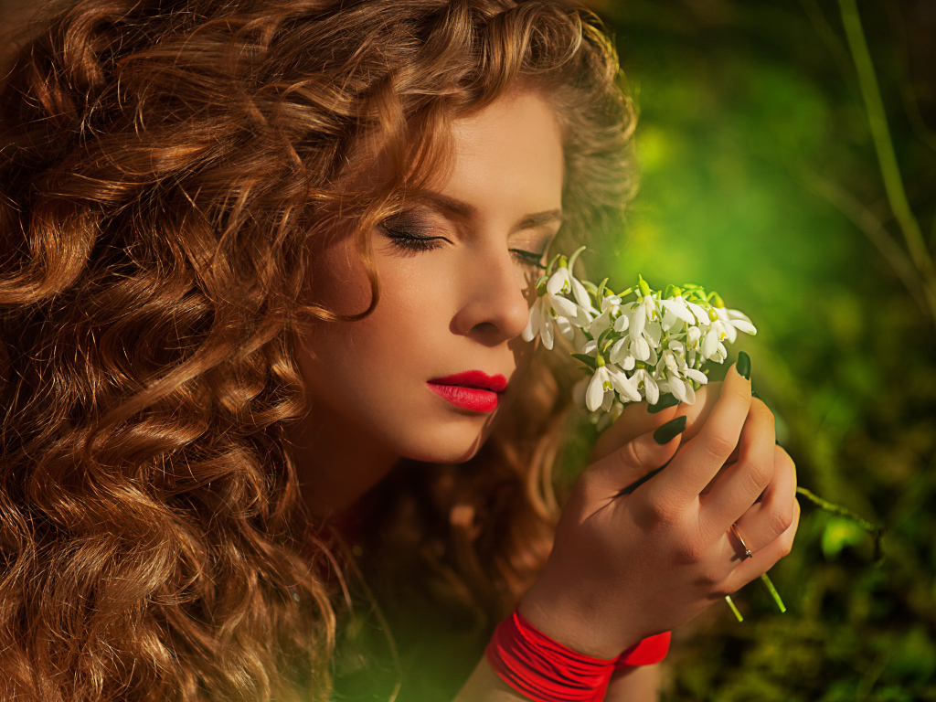 Красивая рыжеволосая девушка с букетом подснежников в руках