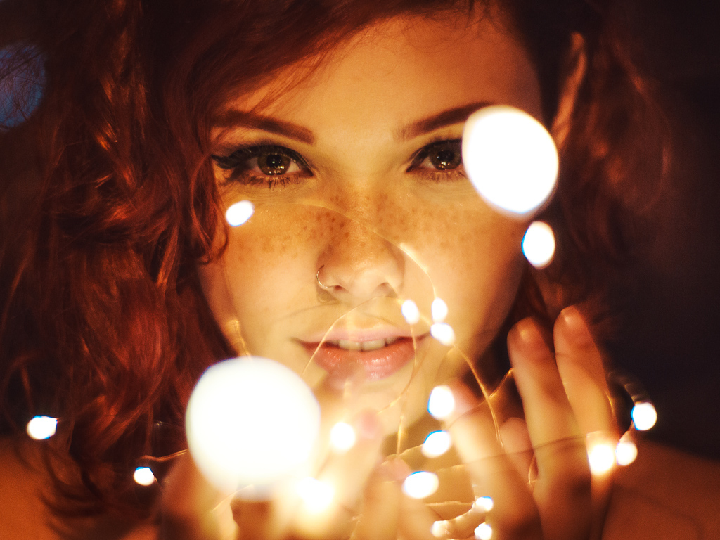 Красивая рыжеволосая девушка с гирляндой в руках 