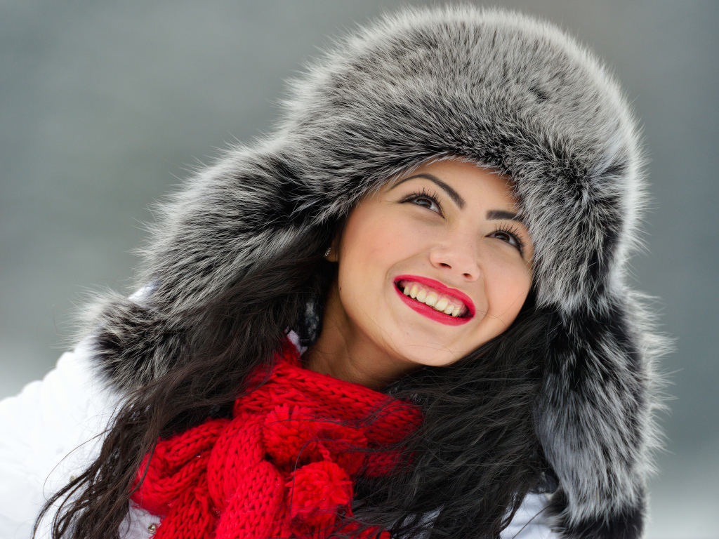 Красивая улыбающаяся брюнетка в теплой зимней шапке