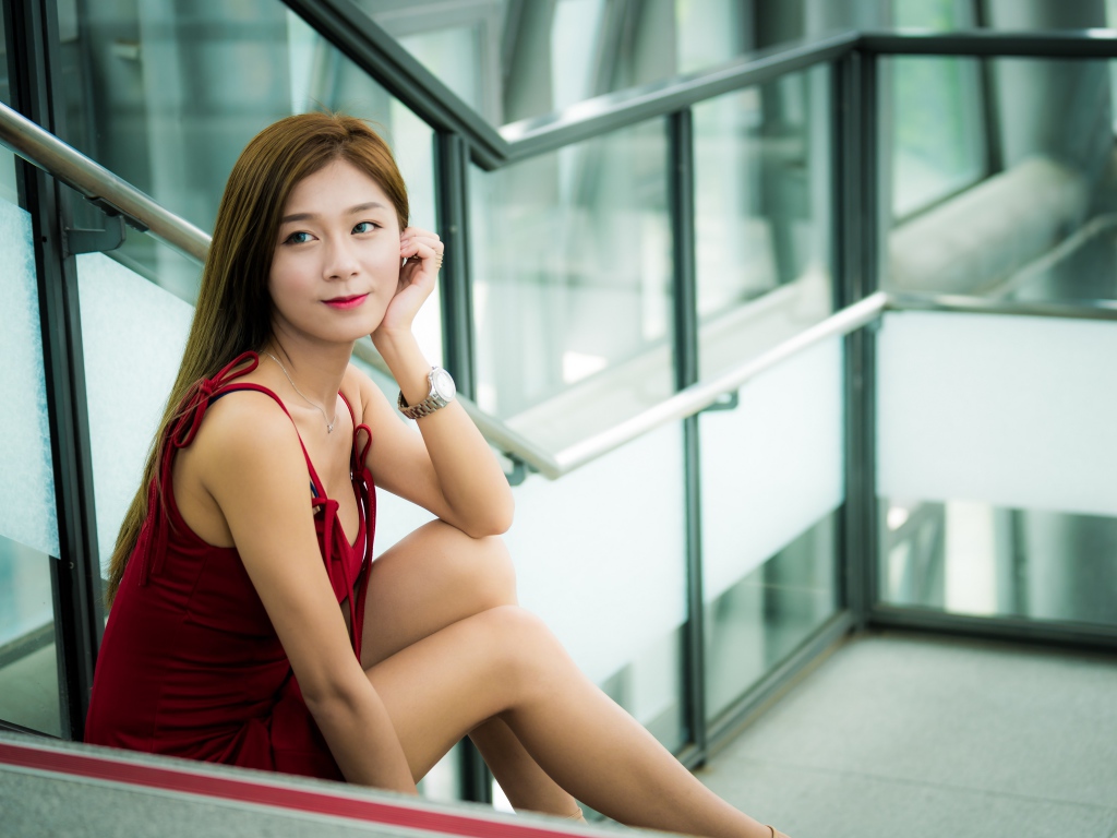 Красивая молодая девушка азиатка сидит на ступенях