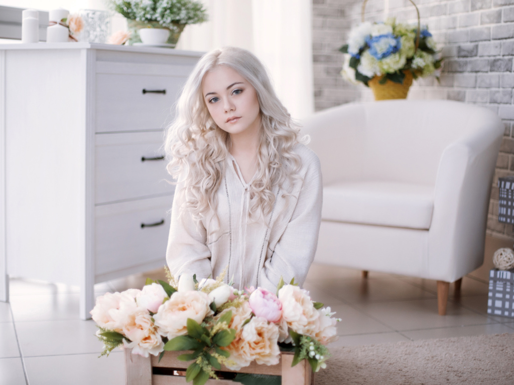 Девушка блондинка с пионами сидит в комнате