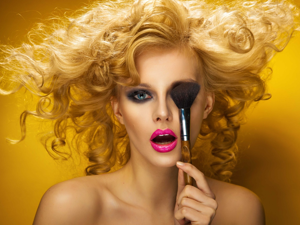 Блондинка с ярким макияжем с кистью у лица