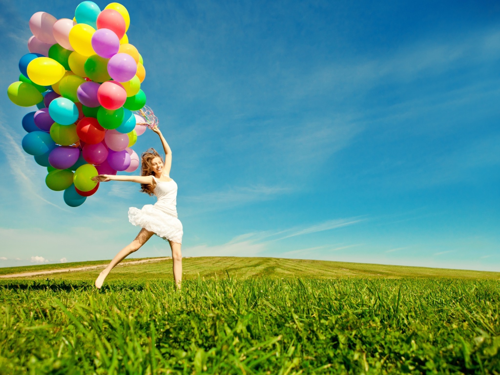 Веселая девушка в белом платье с разноцветными воздушными шариками