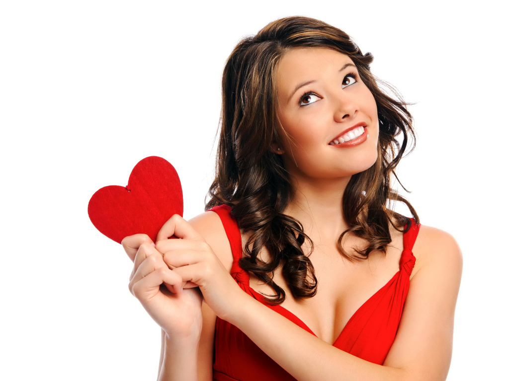 Улыбающаяся девушка с красным сердечком в руках на белом фоне