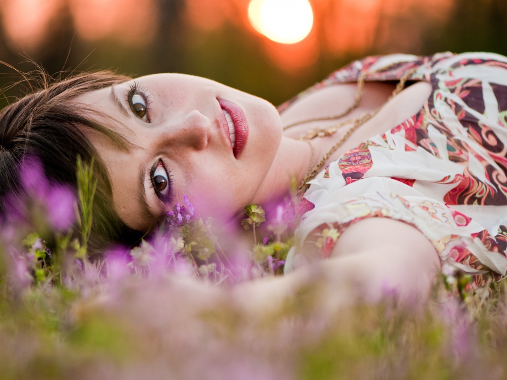 Молодая кареглазая девушка лежит на траве