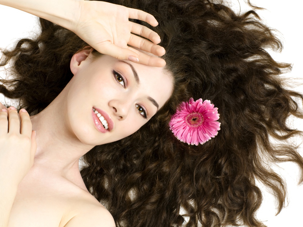 Молодая шатенка с розовым цветком герберы в волосах