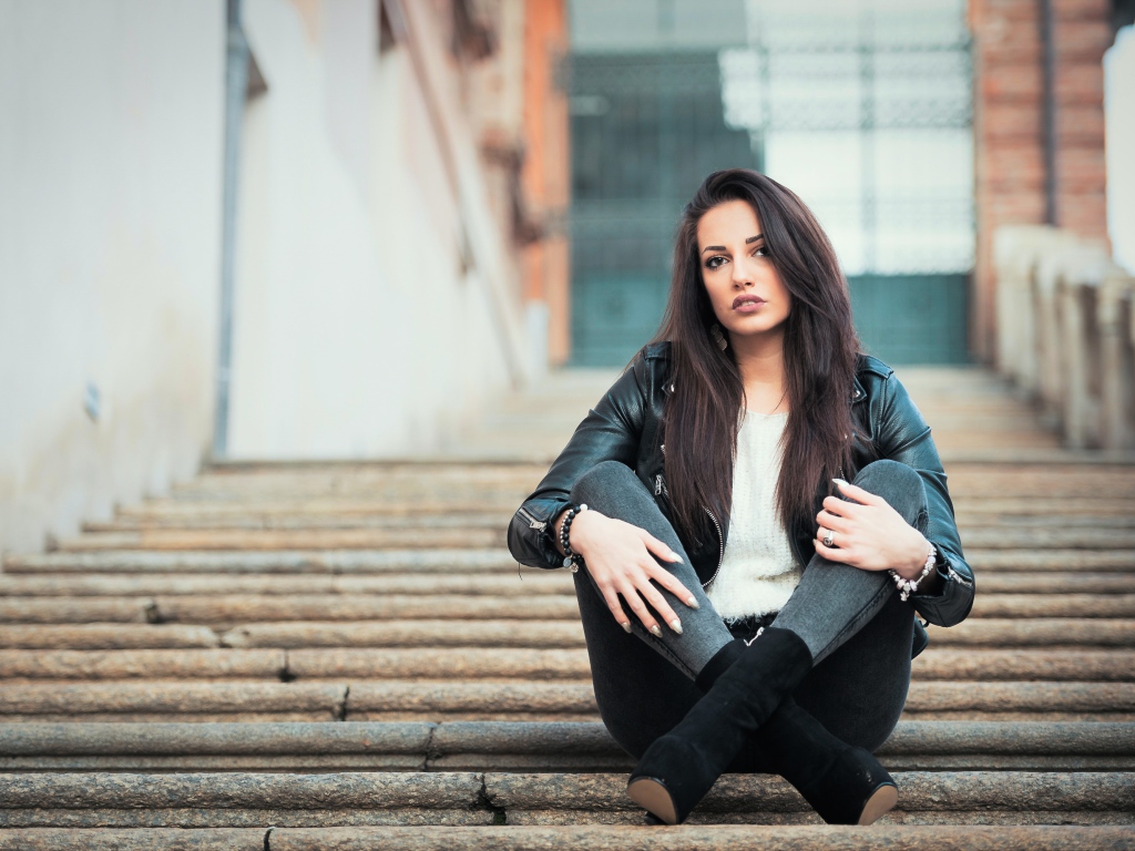 Молодая брюнетка сидит на ступеньках