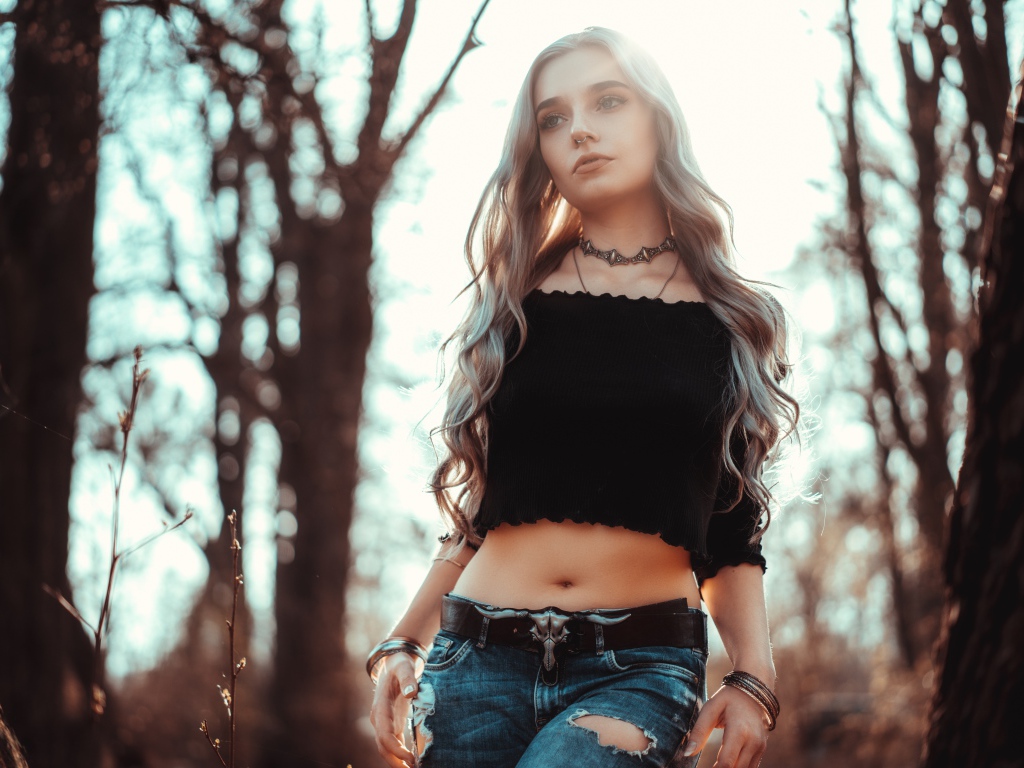 Молодая девушка в рваных джинсах с пирсингом в носу