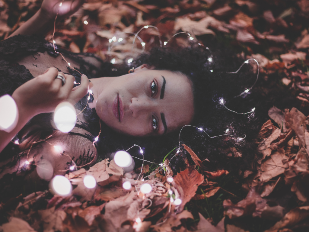 Молодая девушка лежит с гирляндой на желтых листьях