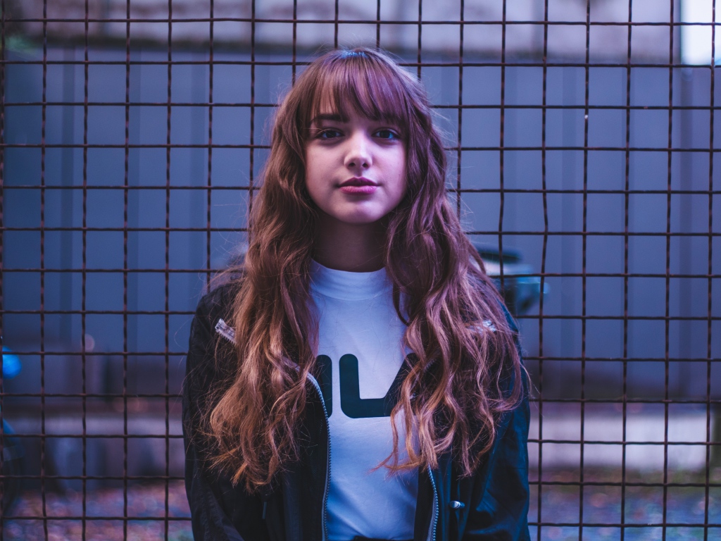 Молодая девушка на фоне железной сетки