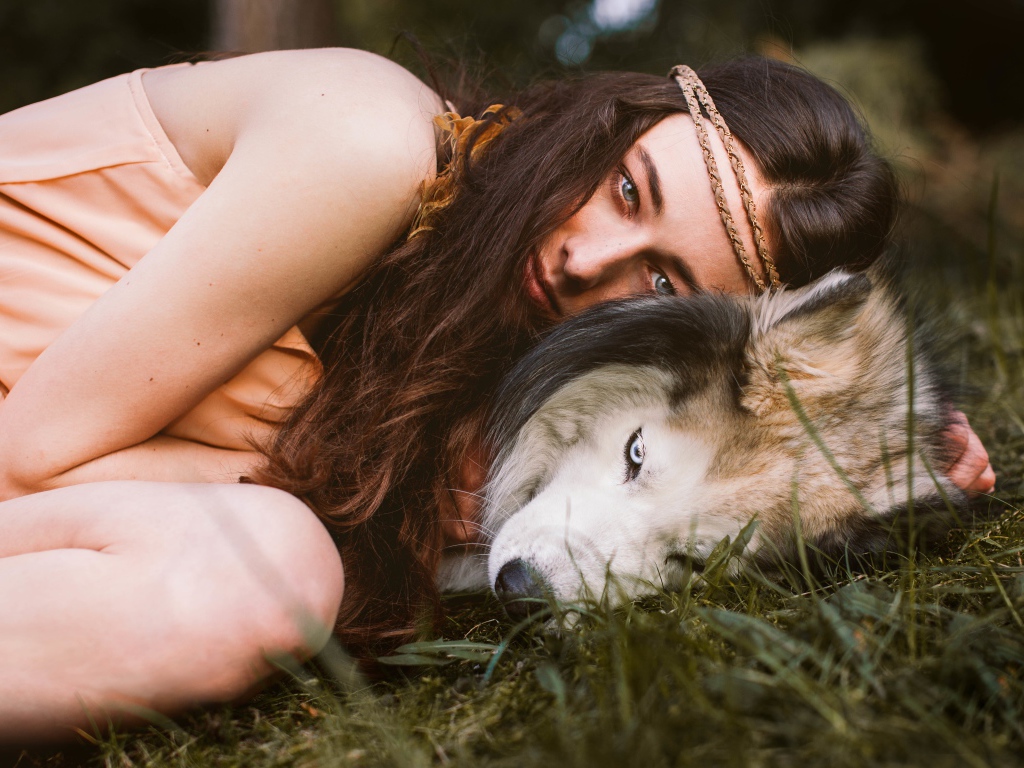 Молодая девушка с собакой породы хаски лежит на траве