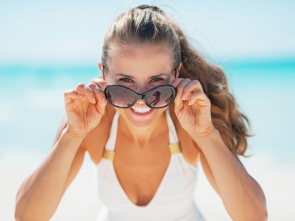 Молодая улыбающаяся девушка в солнечных очках 