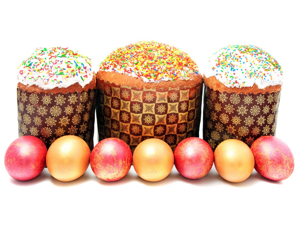 Три пасхальных кулича с крашеными яйцами на белом фоне на праздник Пасха