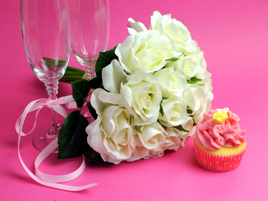 Букет белых роз, пирожное и два бокала на розовом фоне на 8 марта